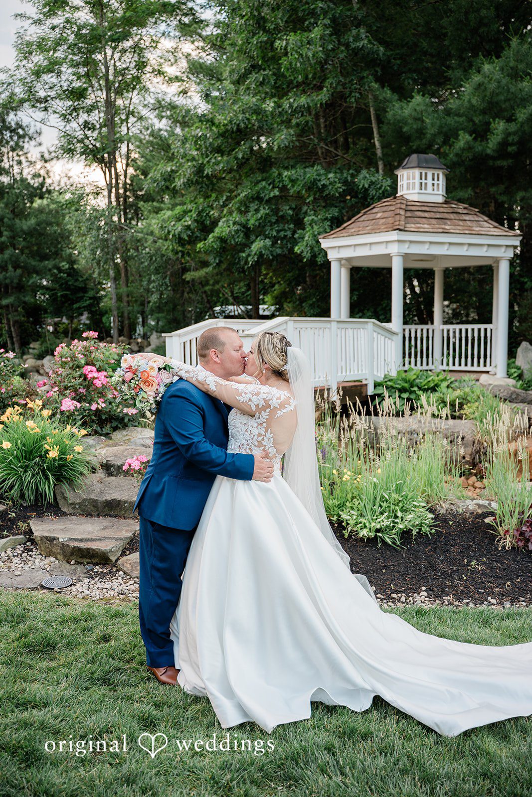 Jessica + Patrick A groom dips his bride for a romantic kiss on a lawn near a garden.