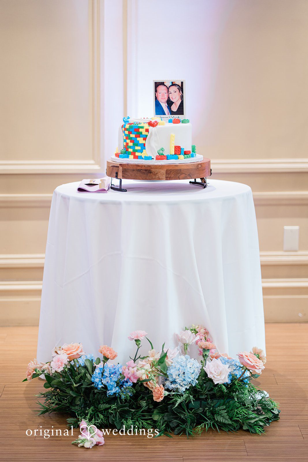 Jessica + Patrick A multi-tiered wedding cake displayed on a round table with a white tablecloth.