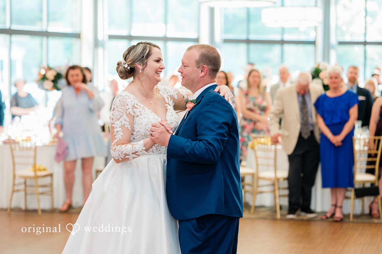 Jessica + Patrick A bride and groom share a dance while surrounded by standing reception guests.