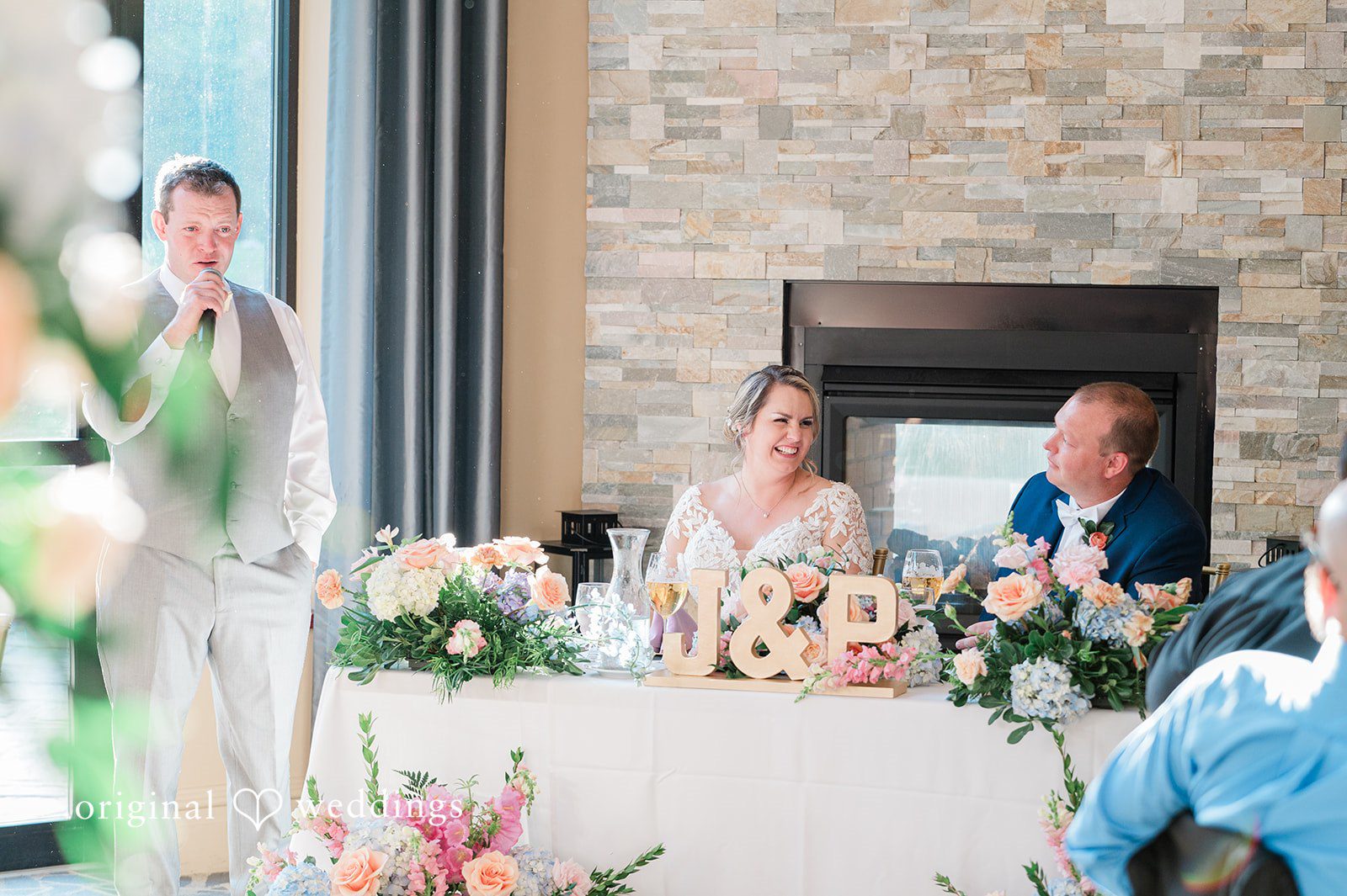 Jessica + Patrick A bride and groom sit together at a decorated sweetheart table during their reception.
