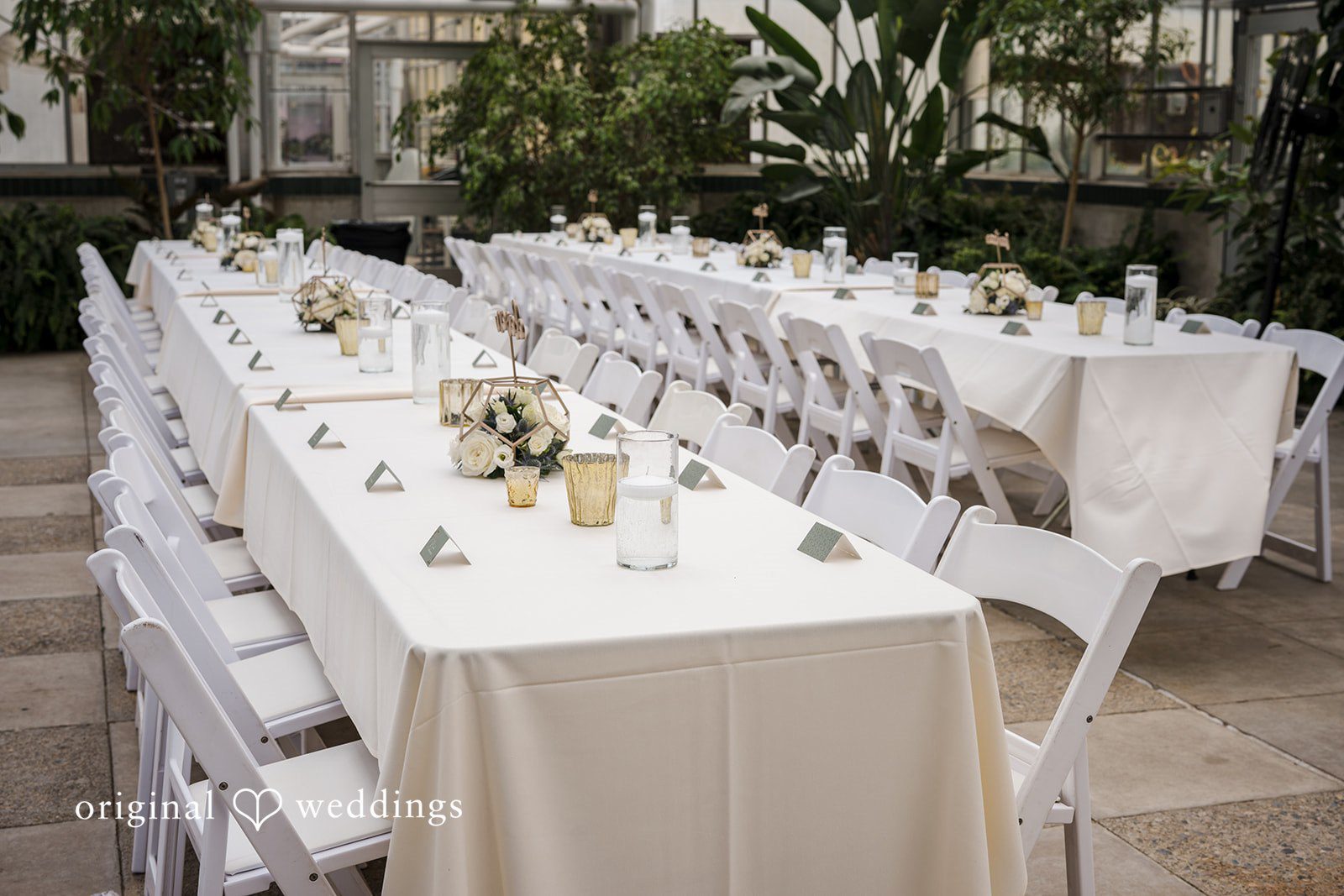 Emily + Maxwell A long reception table set with white linens, candles, and glassware.