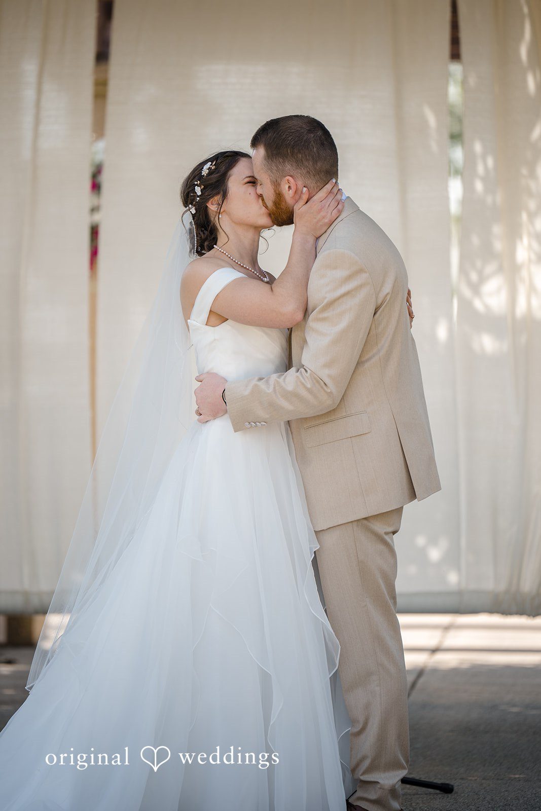 Emily + Maxwell A bride and groom sharing a close embrace and kiss during their wedding.