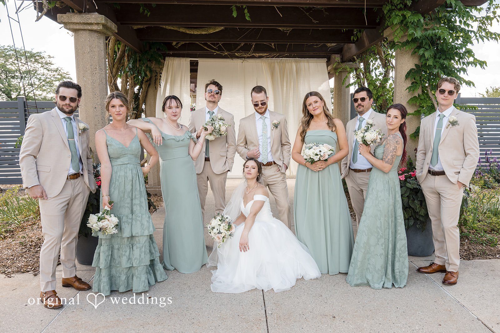 Emily + Maxwell A wedding party standing together under a shaded canopy structure.