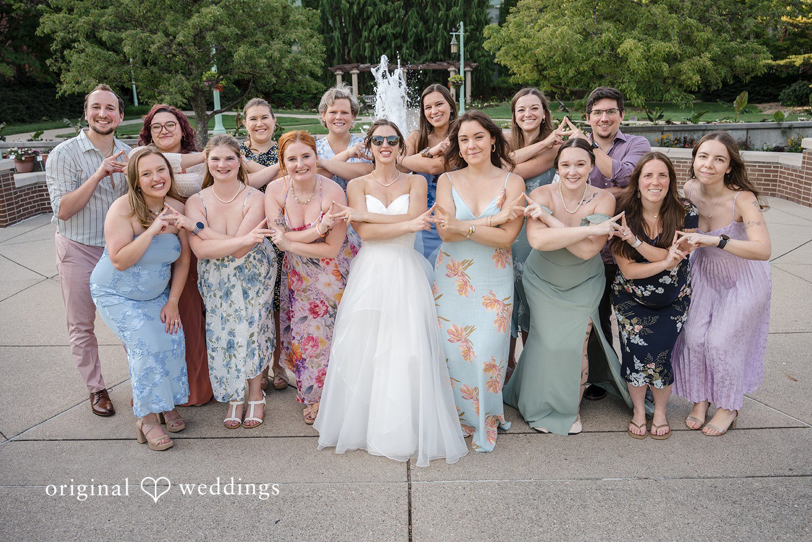 Emily + Maxwell A large group of wedding guests posing together around a bride and groom.