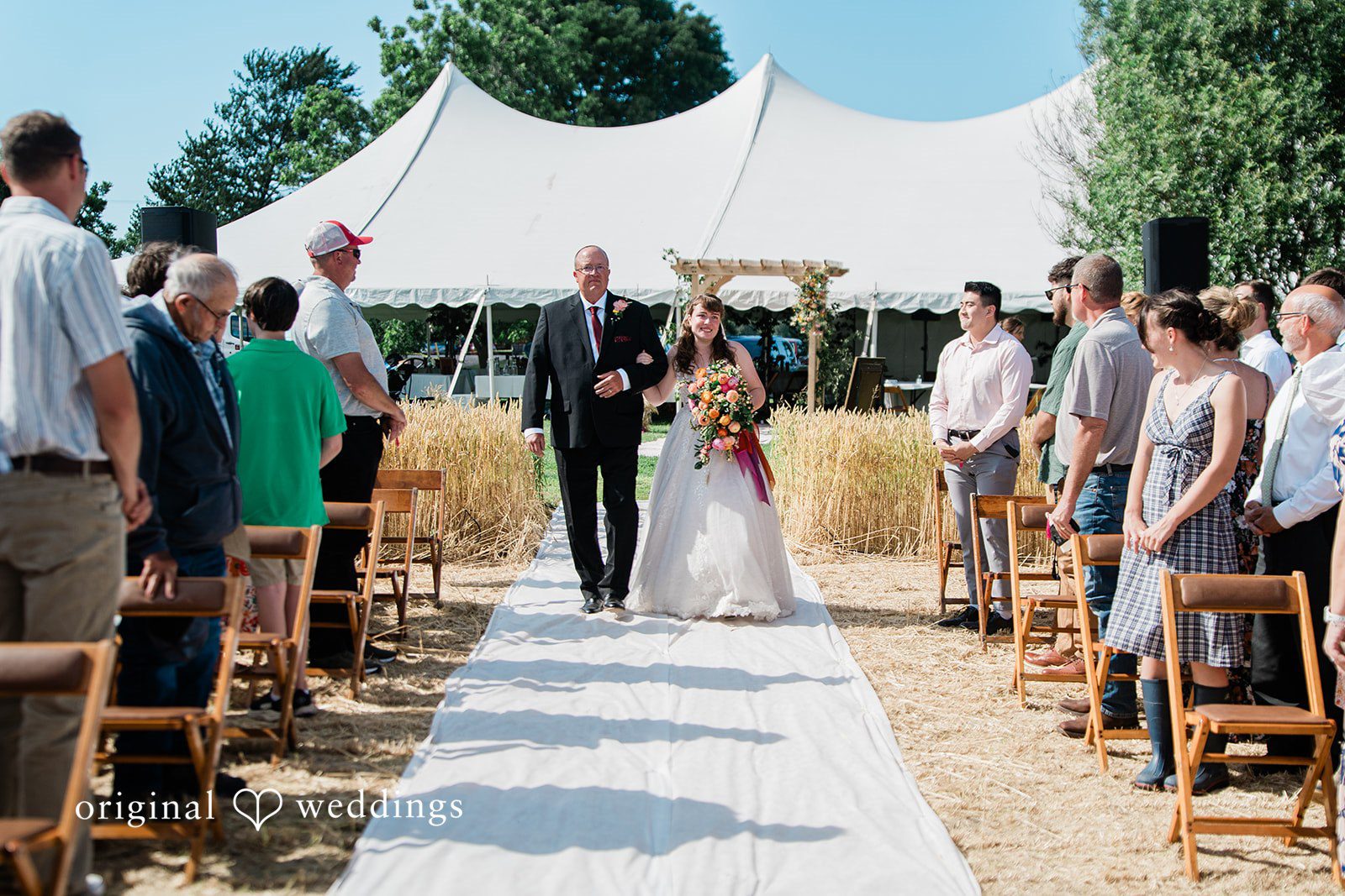 Lovely bride walking down the aisle with someone, arms in arms