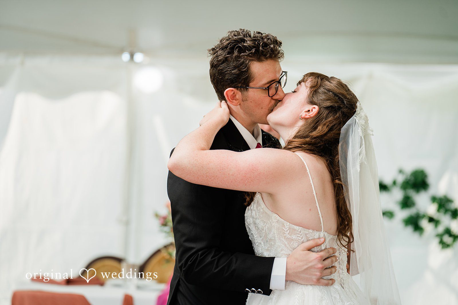 Bride and groom sharing a romantic kiss while dancing in wedding reception