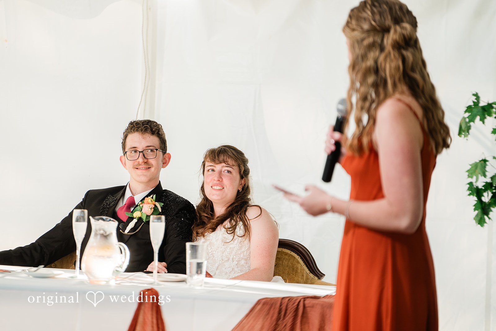 Bride and groom listening to the speech of guest in a wedding reception