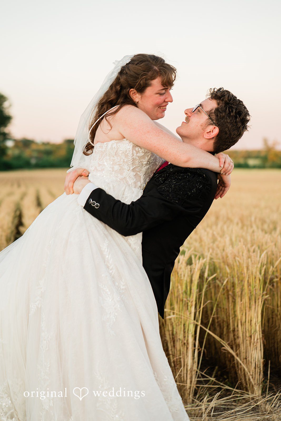 Groom lifting up the bride in a field