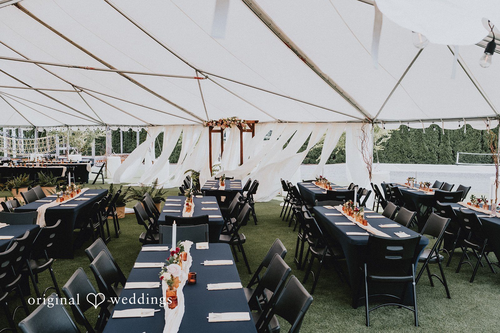 Catherine + Gabriel Long reception tables set up under a large white event tent.