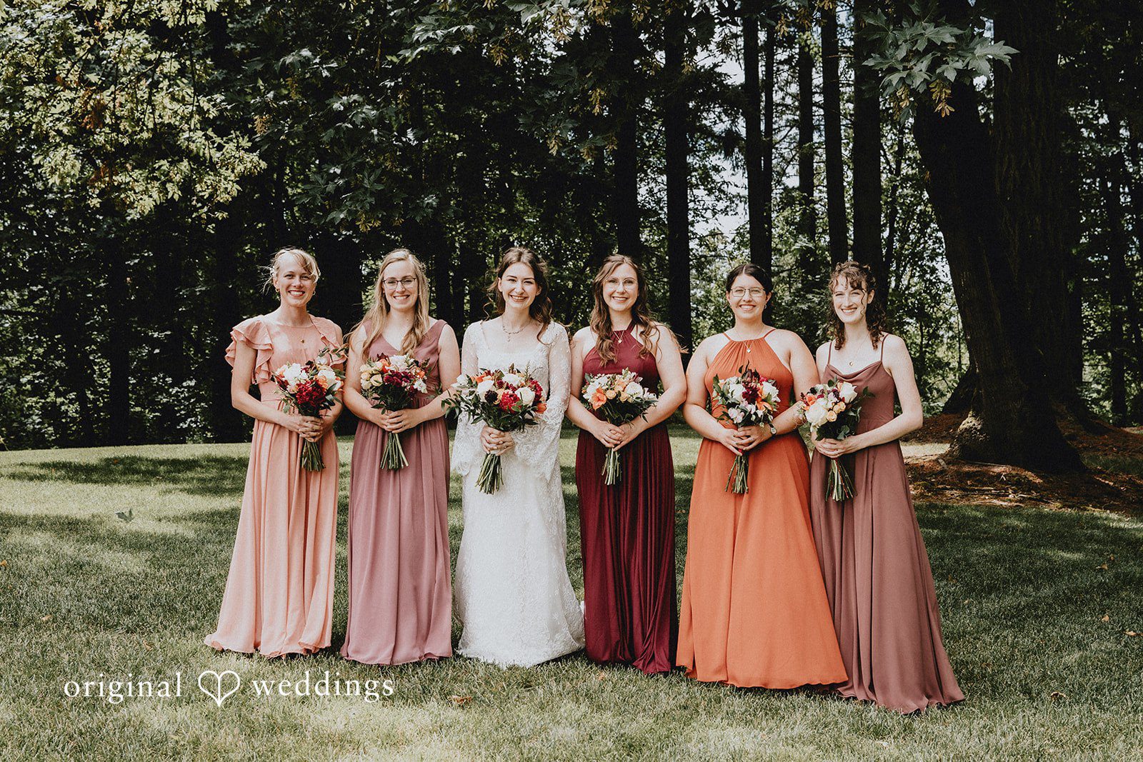Catherine + Gabriel Bride and bridesmaids standing together in matching earthy terracotta and rust-toned dresses.