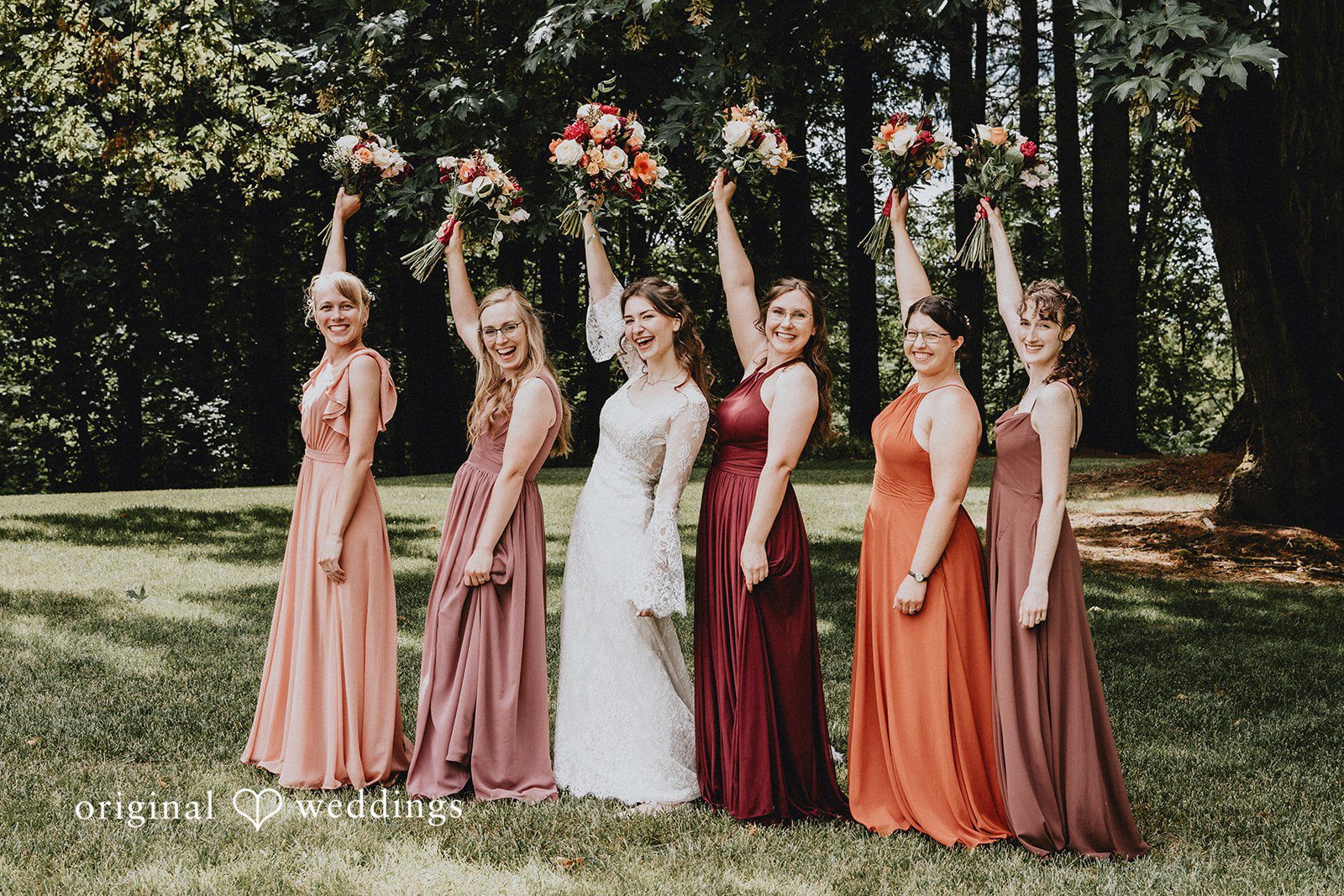 Catherine + Gabriel Bridesmaids standing in a line holding bouquets in front of trees.