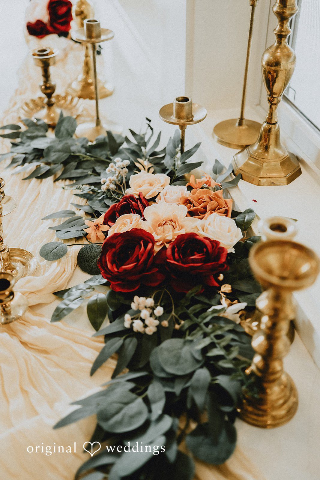 Catherine + Gabriel Table arrangement decorated with dark red roses and eucalyptus leaves.