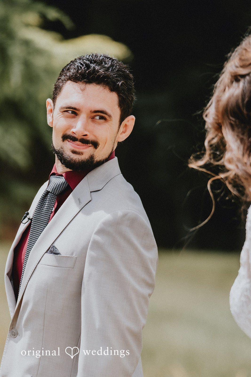 Catherine + Gabriel Groom in a grey suit glancing back over his shoulder toward the bride.