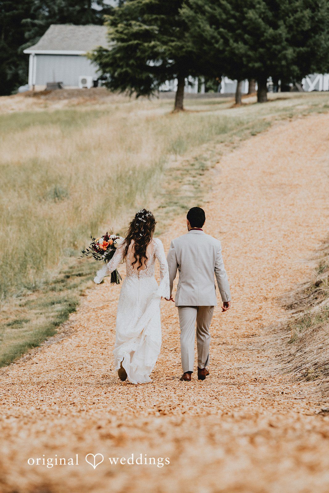Catherine + Gabriel Bride and groom walking hand-in-hand down a wide dirt path away.