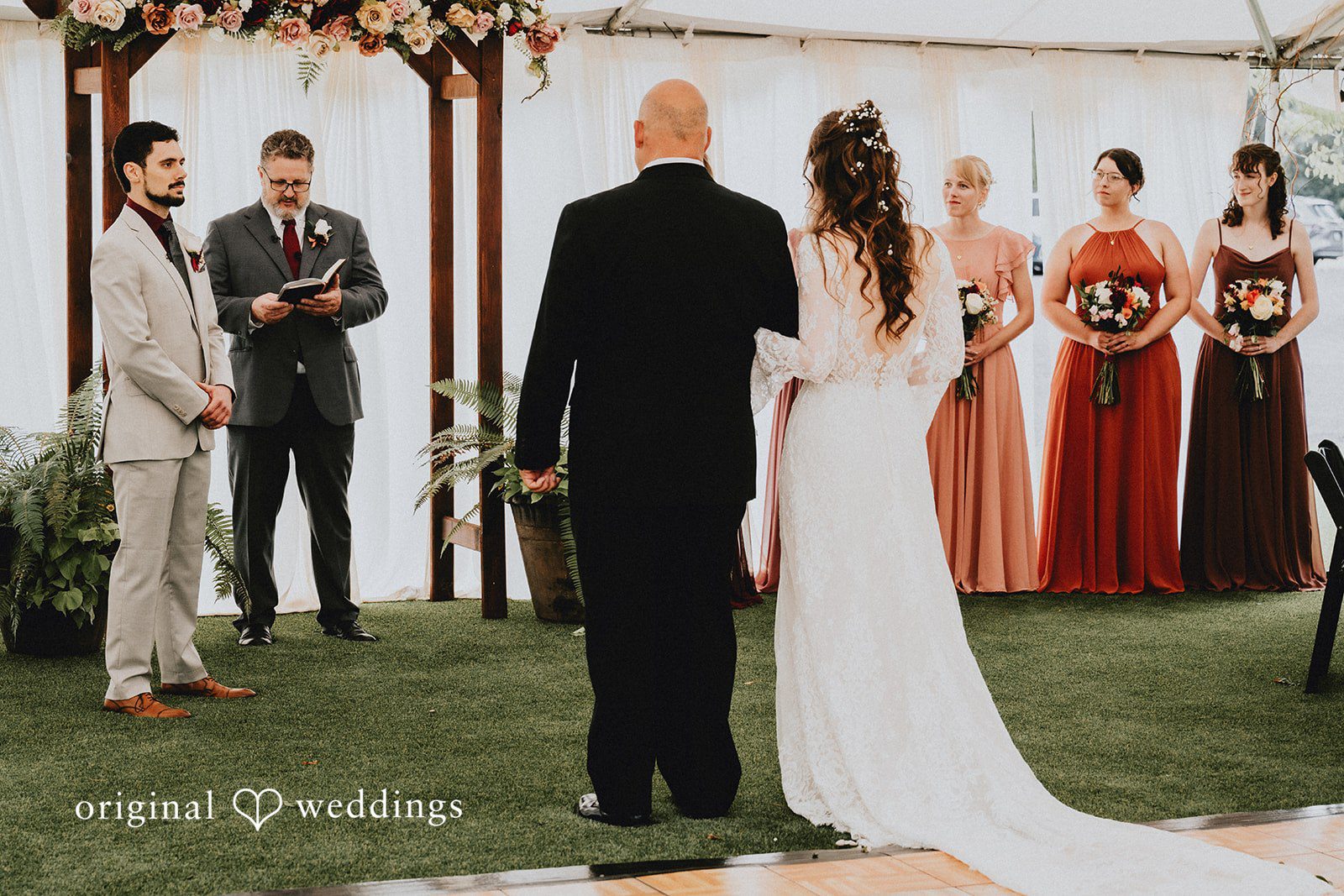 Catherine + Gabriel Bride walking away toward an altar with the wedding party watching.