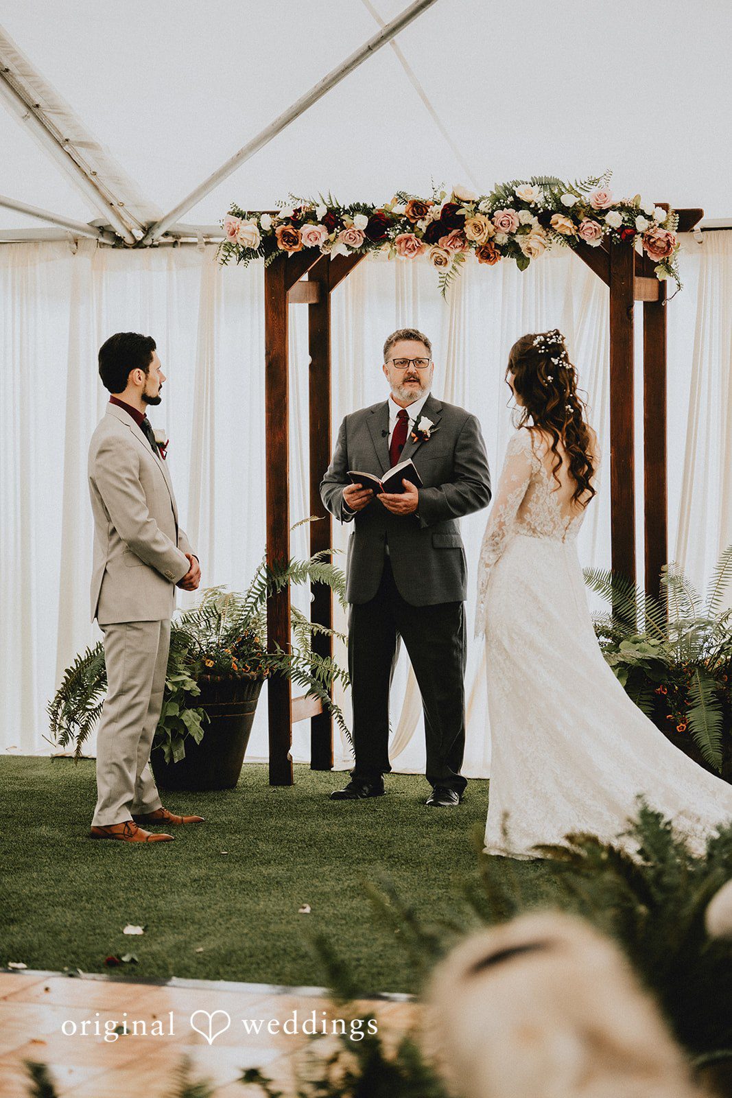 Catherine + Gabriel Wedding ceremony taking place in front of a wooden arbor.