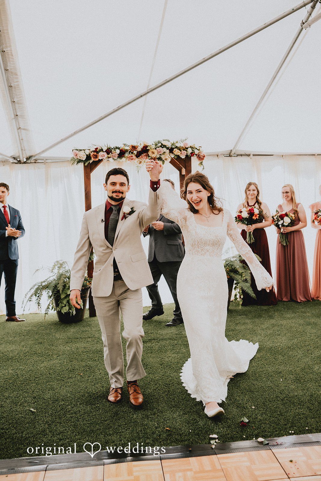 Catherine + Gabriel Newlyweds walking down a wooden aisle together while wedding guests clap in the background.