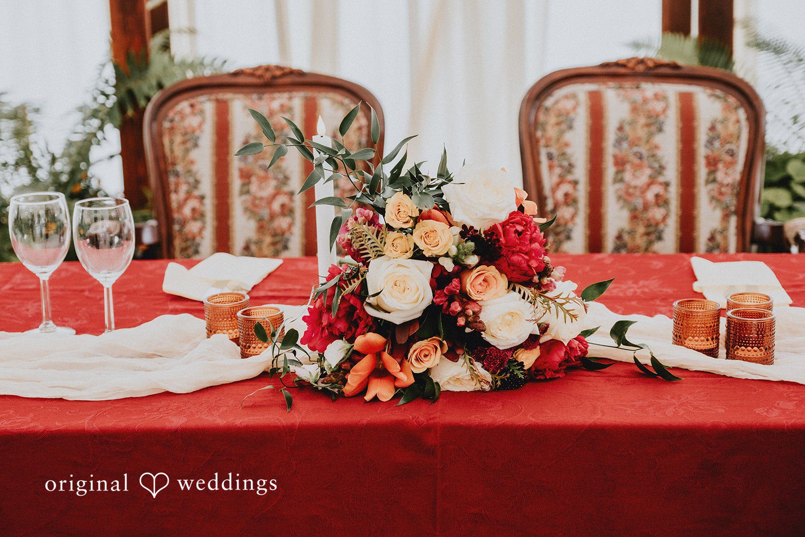 Catherine + Gabriel Elegant dinner table featuring a red tablecloth and floral centerpieces.