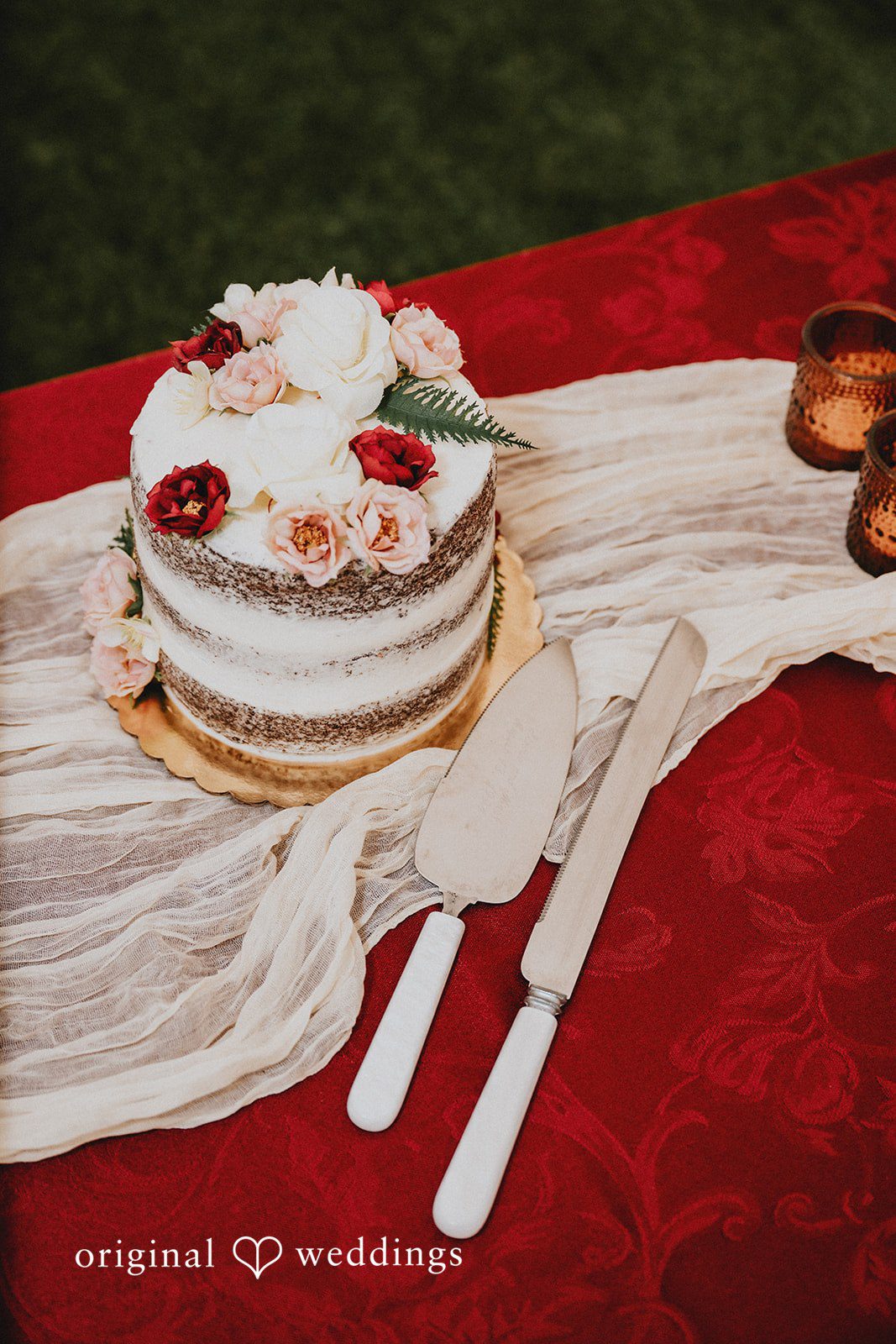 Catherine + Gabriel Small wedding cake placed on a rustic white runner over a red tablecloth.