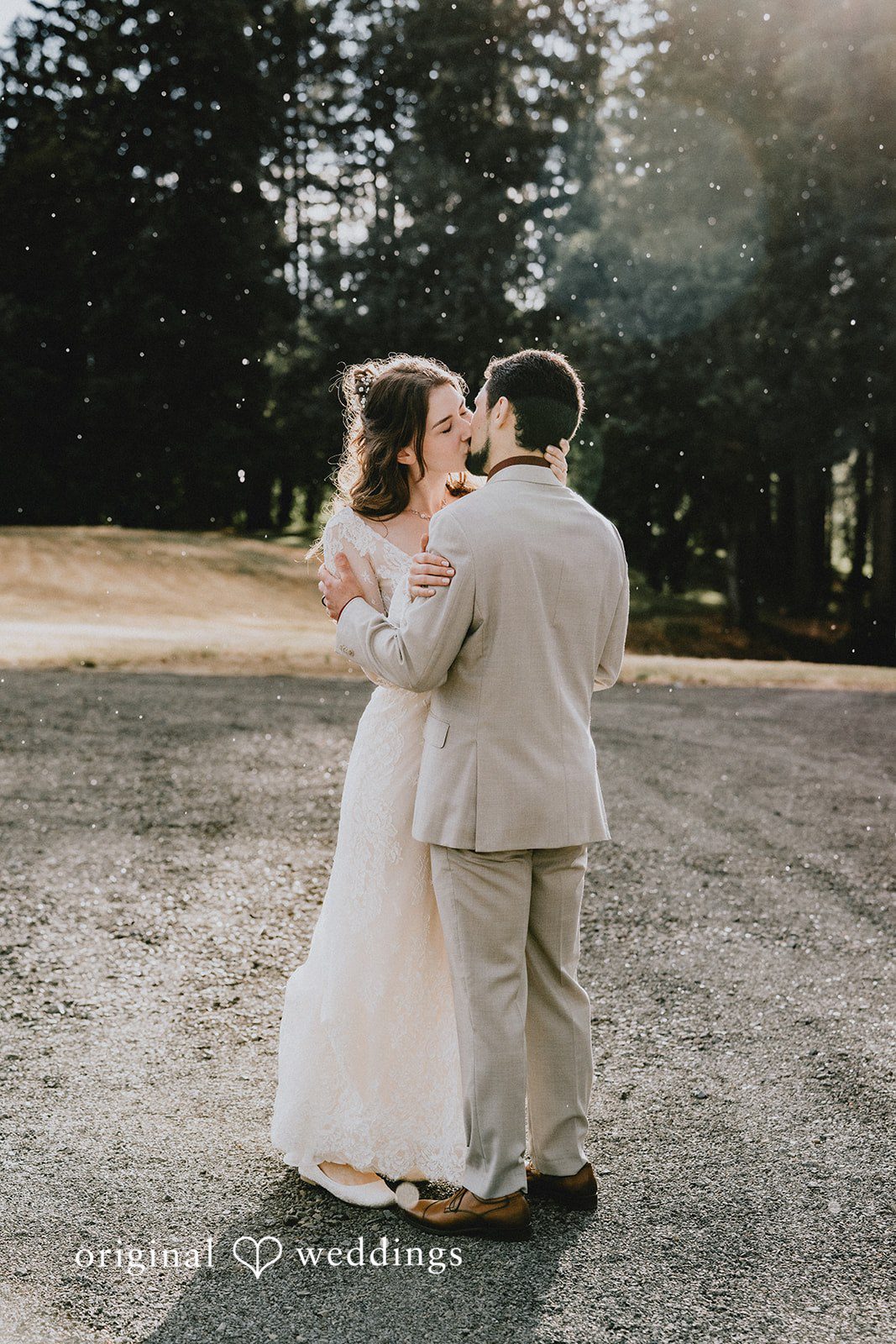 Catherine + Gabriel Bride and groom embracing together on a paved clearing.
