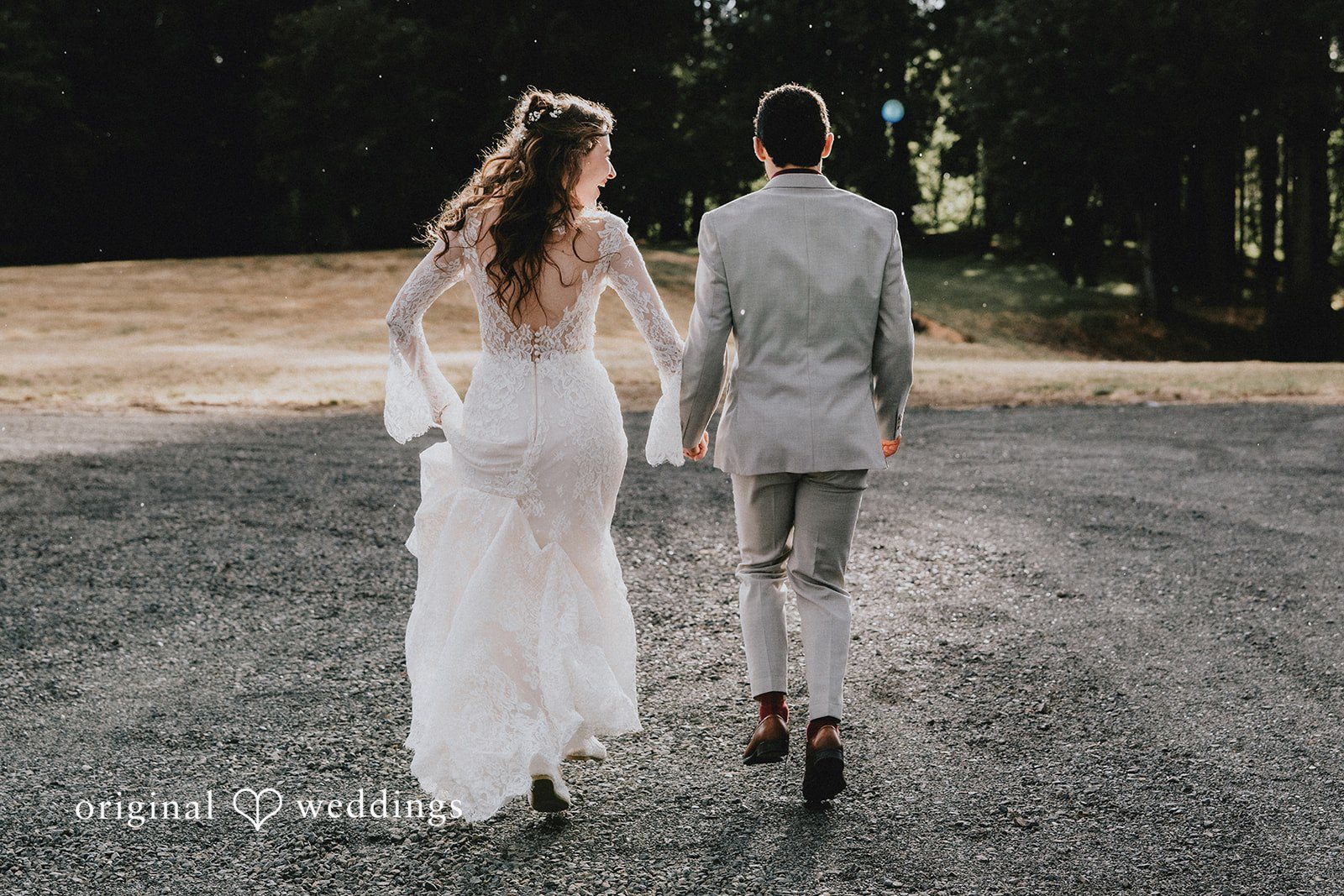 Catherine + Gabriel Bride and groom walking away together down a paved path lined with trees.