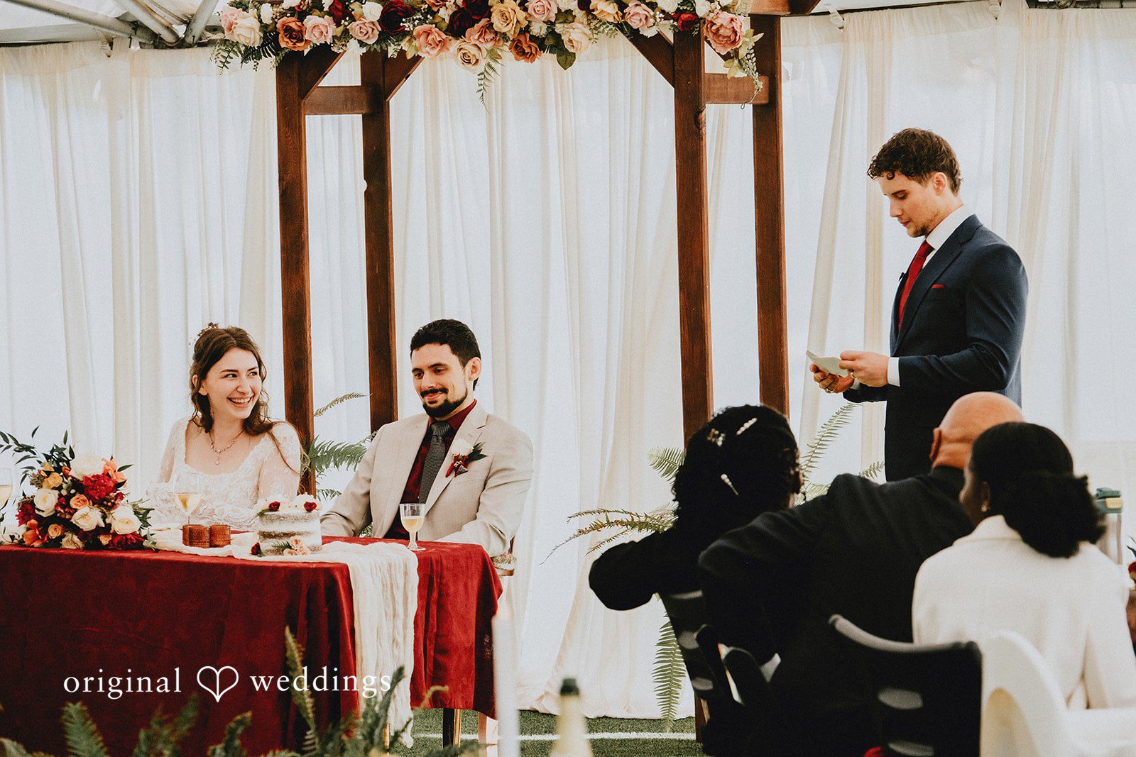Catherine + Gabriel Bride and groom sitting at a decorated head table during their wedding reception.