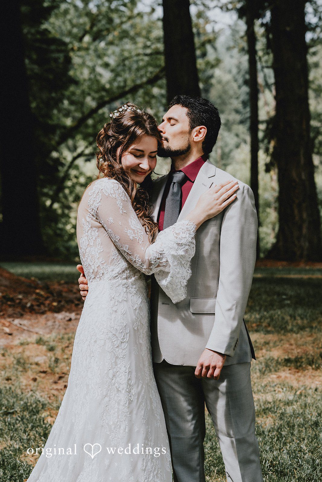 Catherine + Gabriel Groom wrapping his arms around the bride from behind in a forest setting.