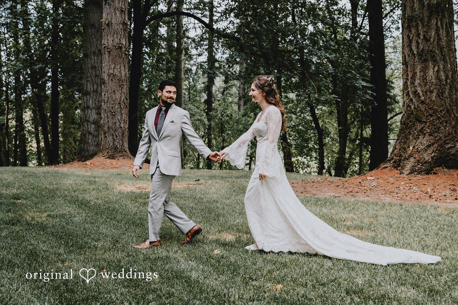 Catherine + Gabriel Bride and groom holding hands while walking through a dense pine forest.