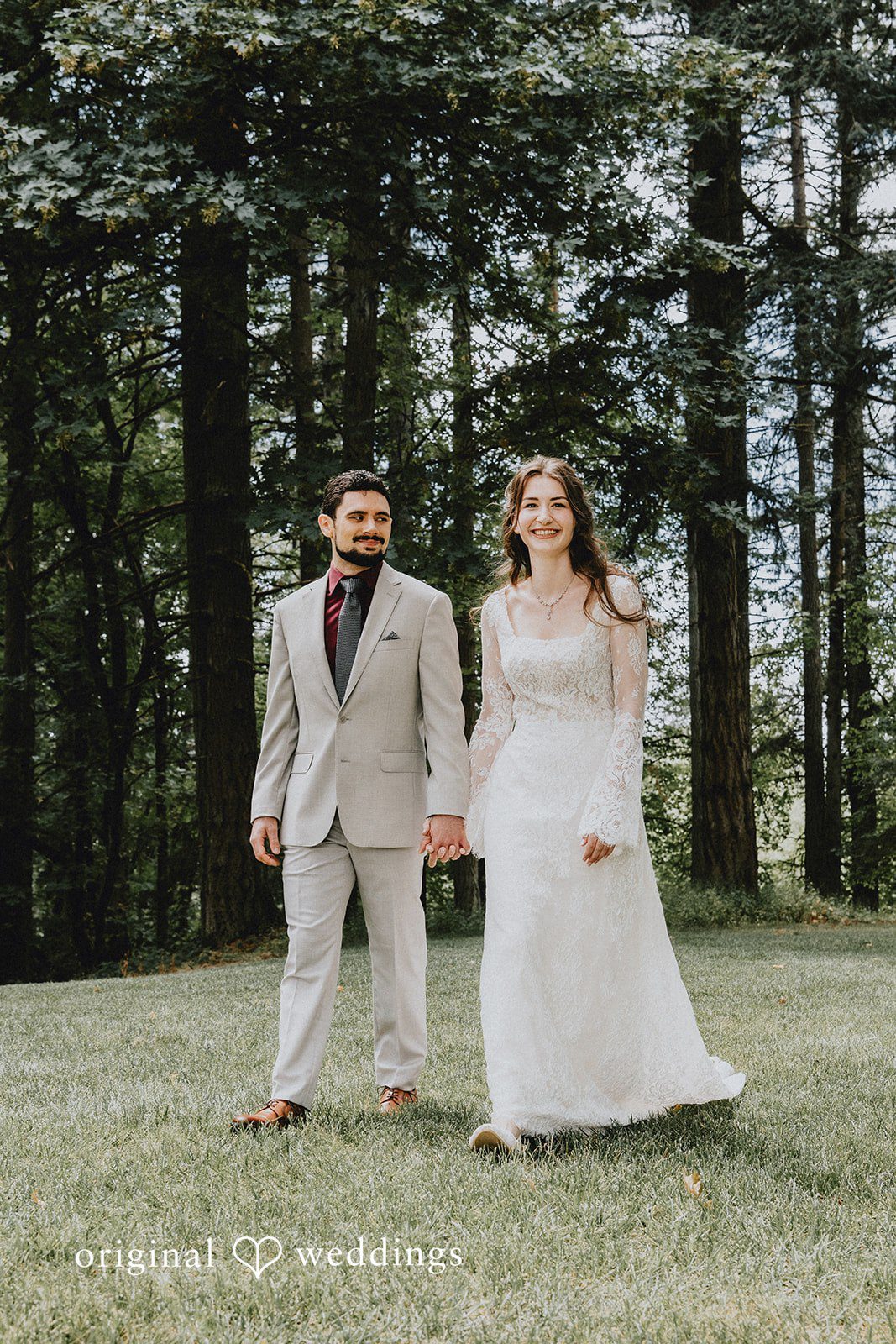 Catherine + Gabriel Newlyweds walking side-by-side along a dirt path surrounded by trees.