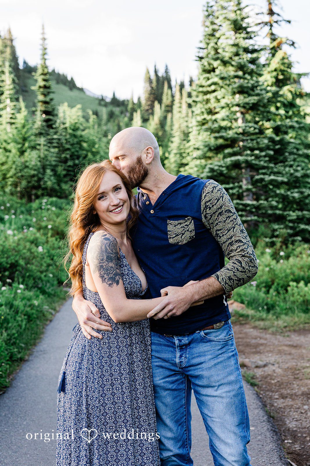 Megan + Kevin A smiling man and a woman embrace closely along a scenic trail.