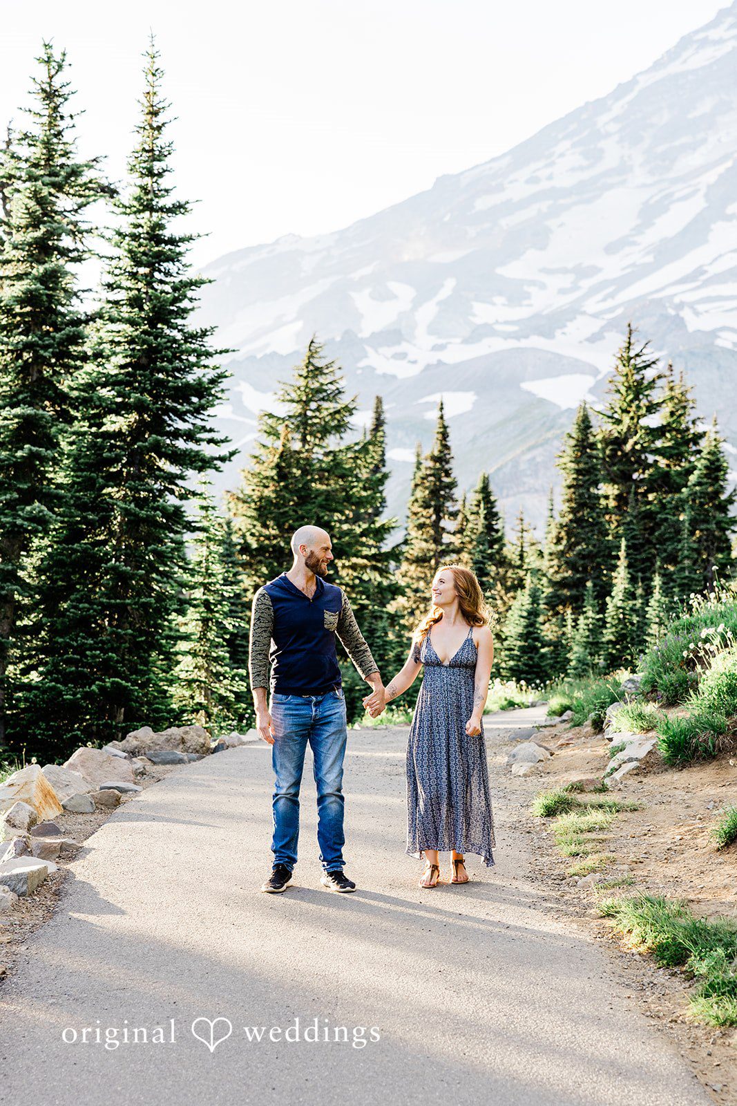Megan + Kevin A man and a woman walk side-by-side down a dirt path leading through green fields.