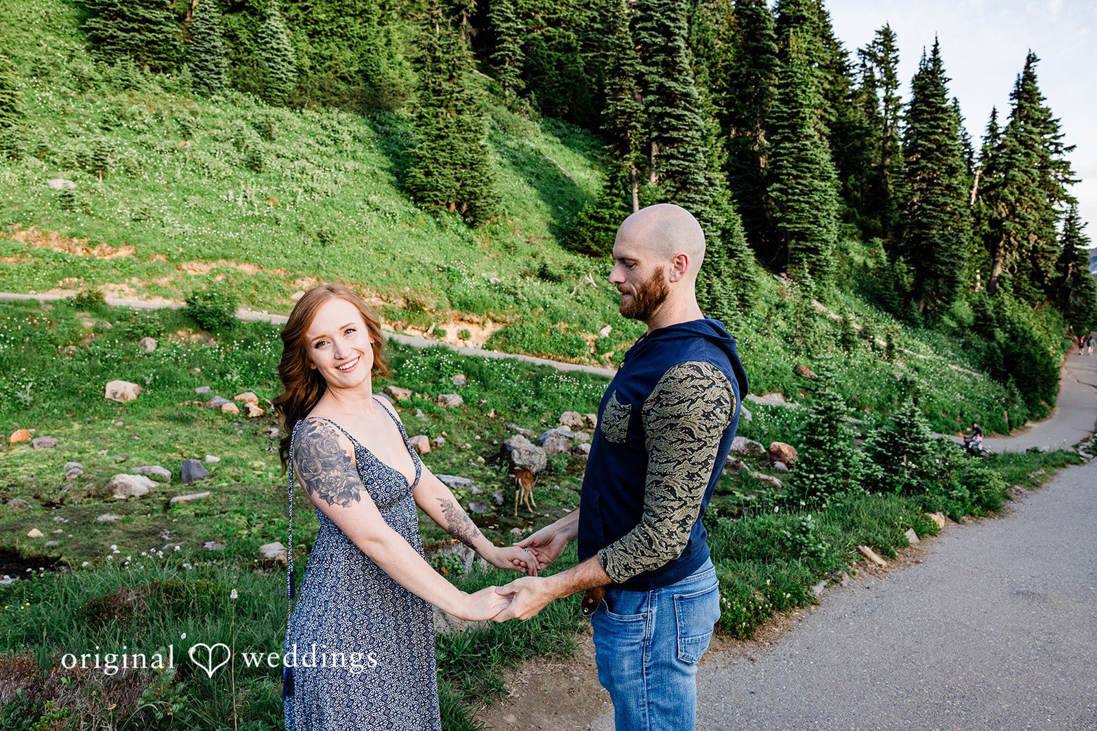 Megan + Kevin A man and a woman hold hands while facing each other on a paved walkway.