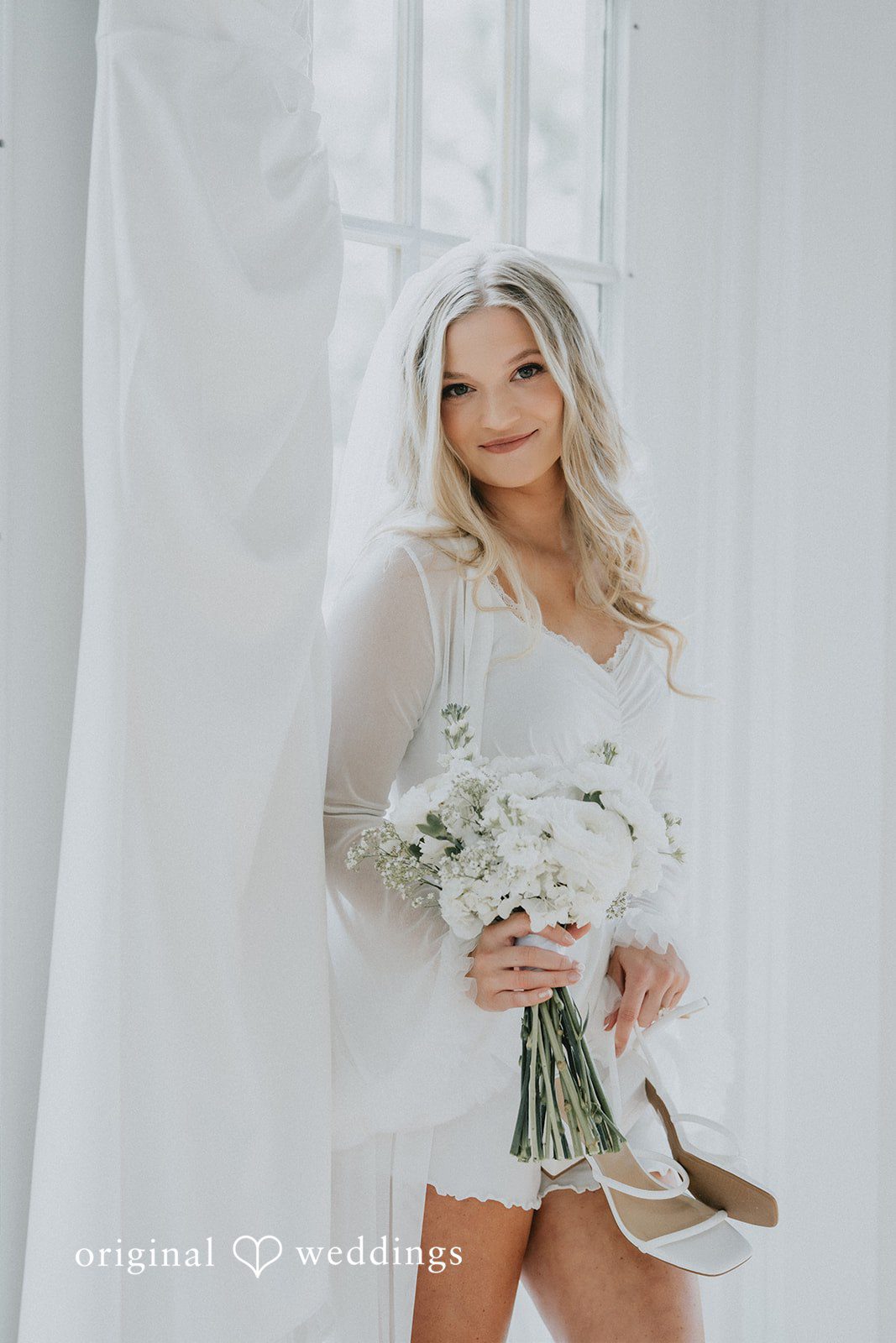 Bride in a lace robe holding her dress at Pine Knob Mansion.