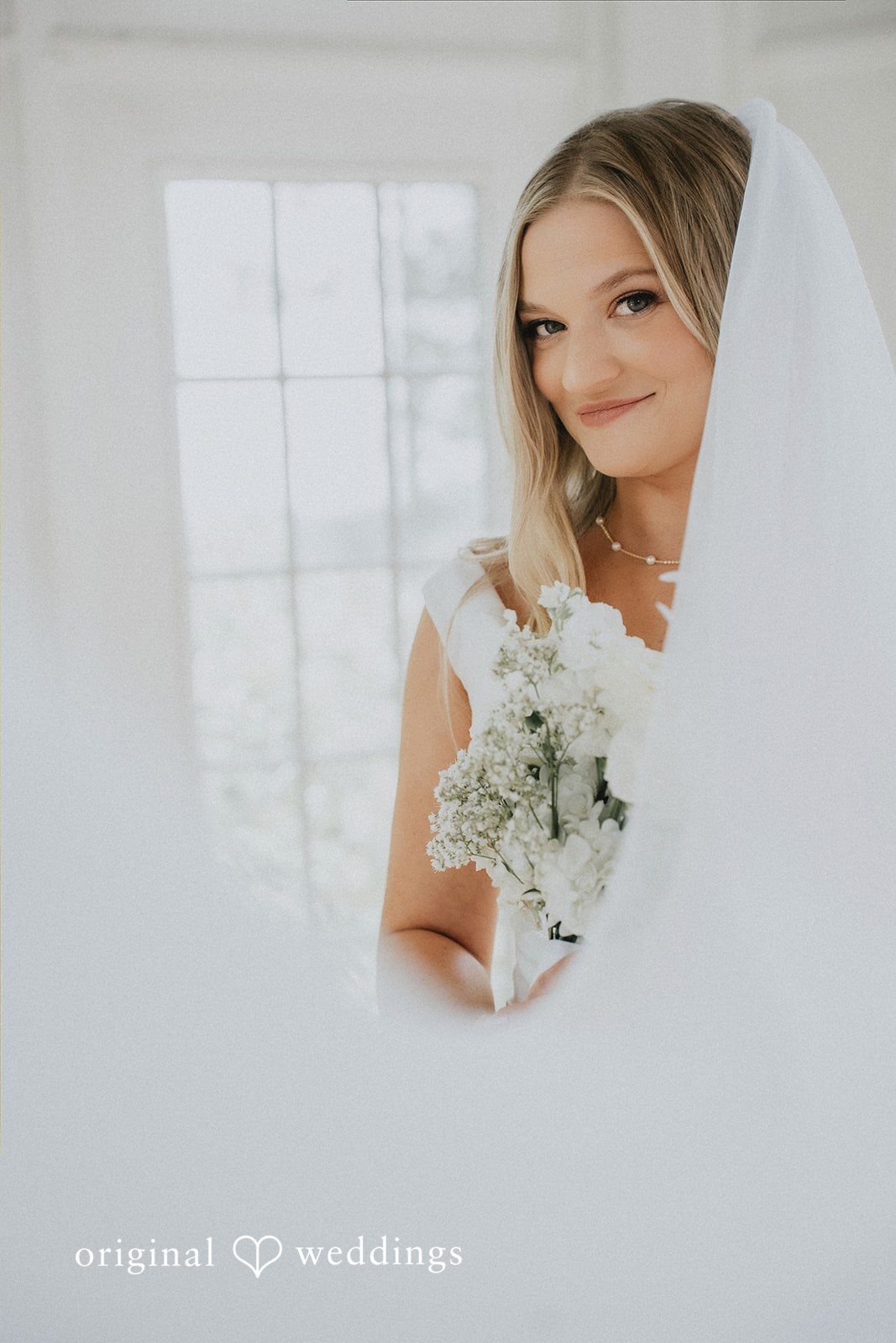 Portrait of a smiling bride wearing a white veil.