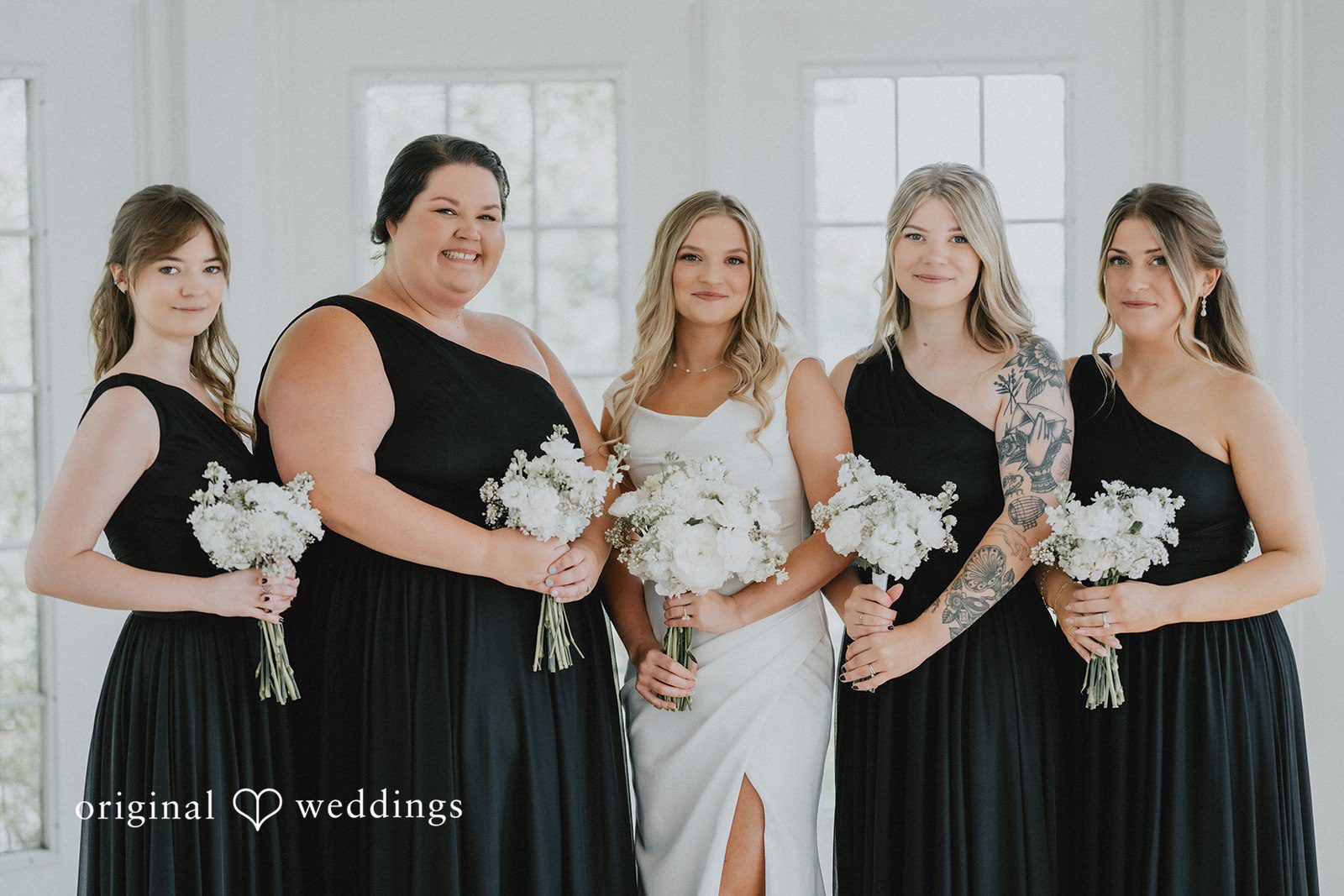 Group of bridesmaids wearing matching black dresses.