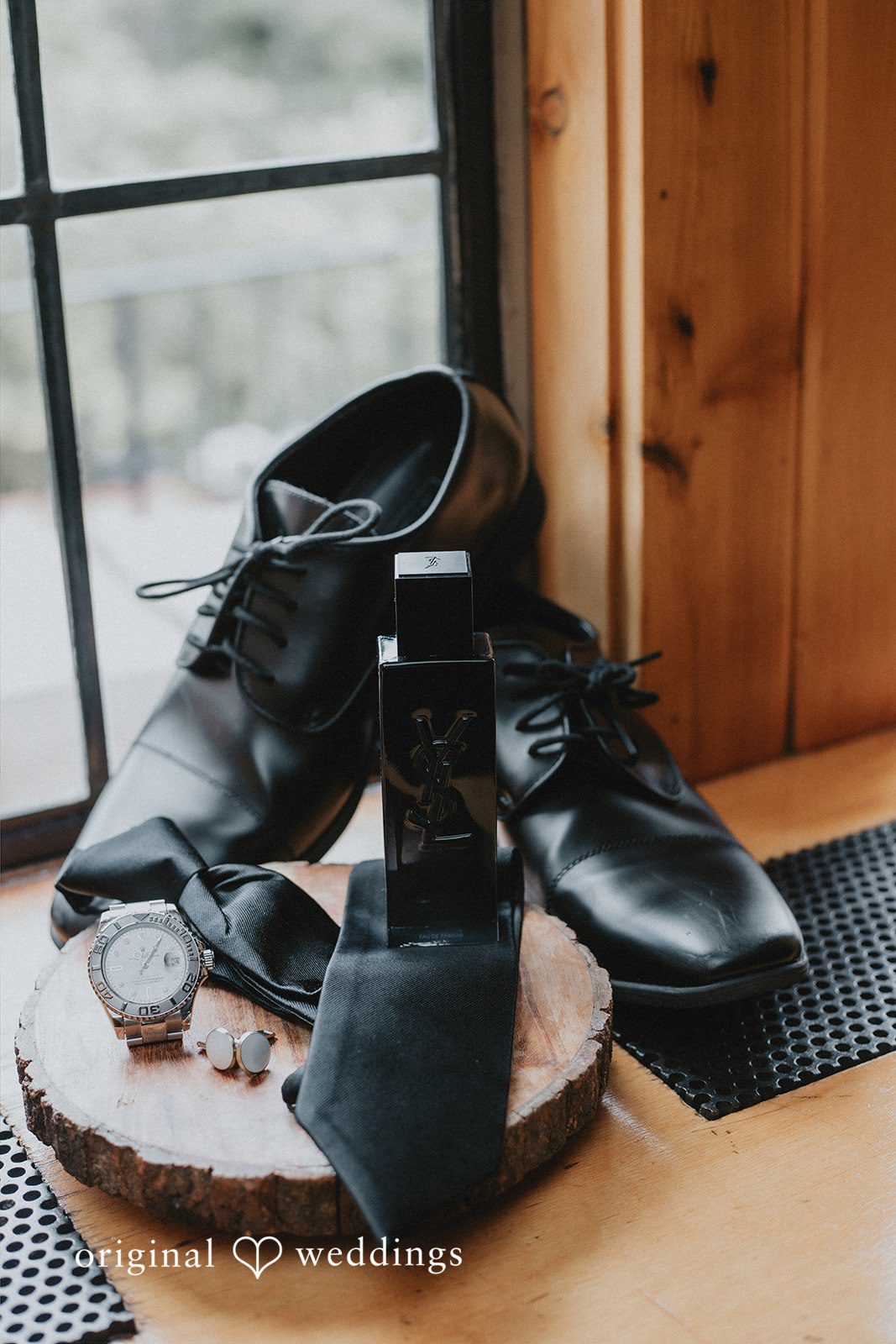 Black dress shoes and accessories placed on wood.