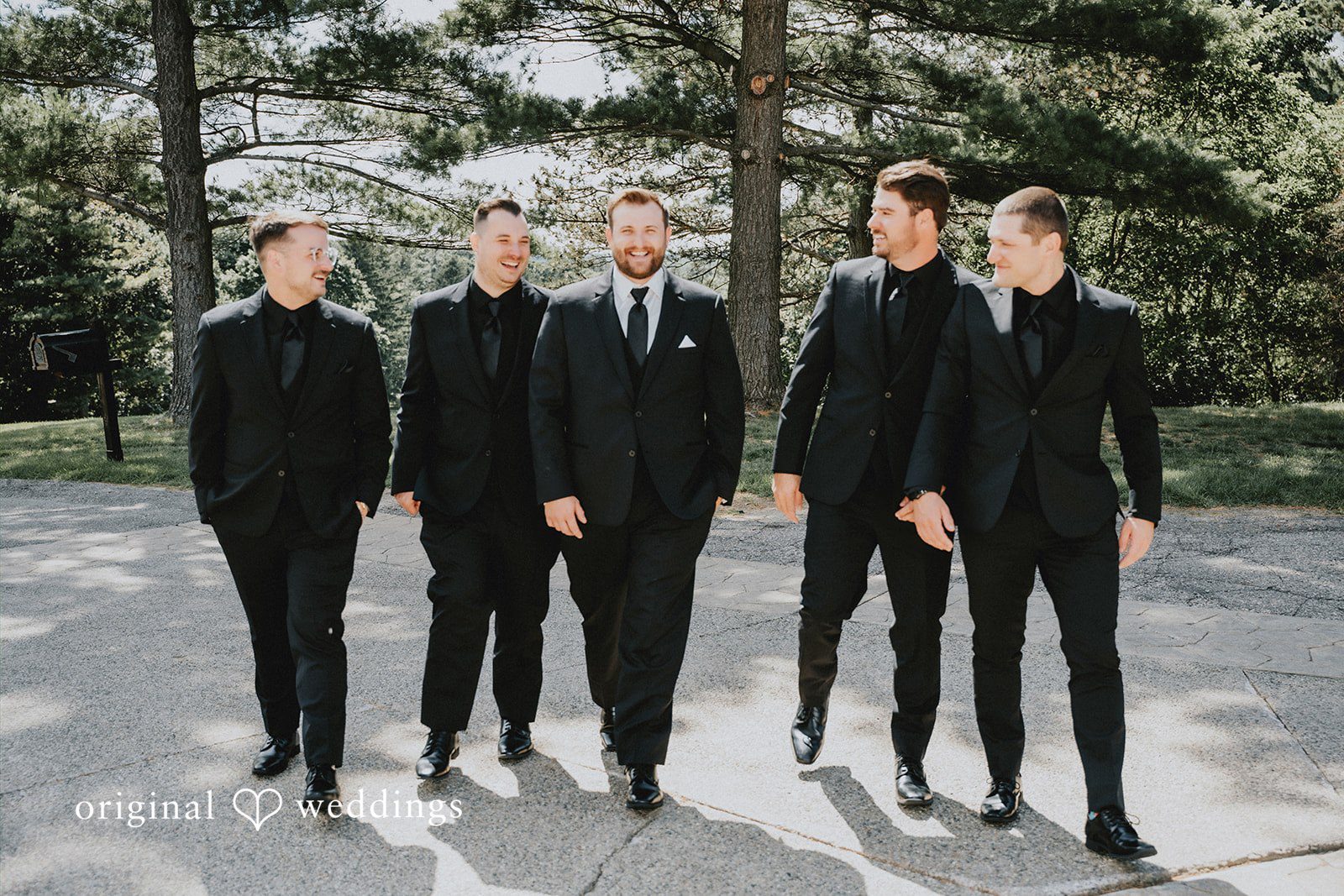 Groom and groomsmen walking together in dark suits.