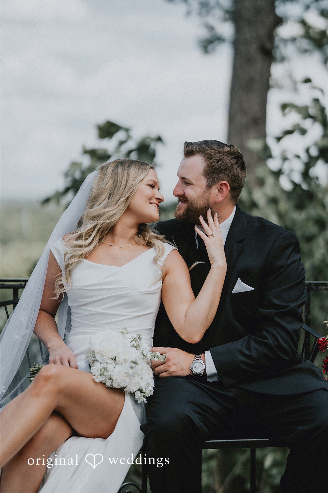 Bride and groom laughing while sitting together.