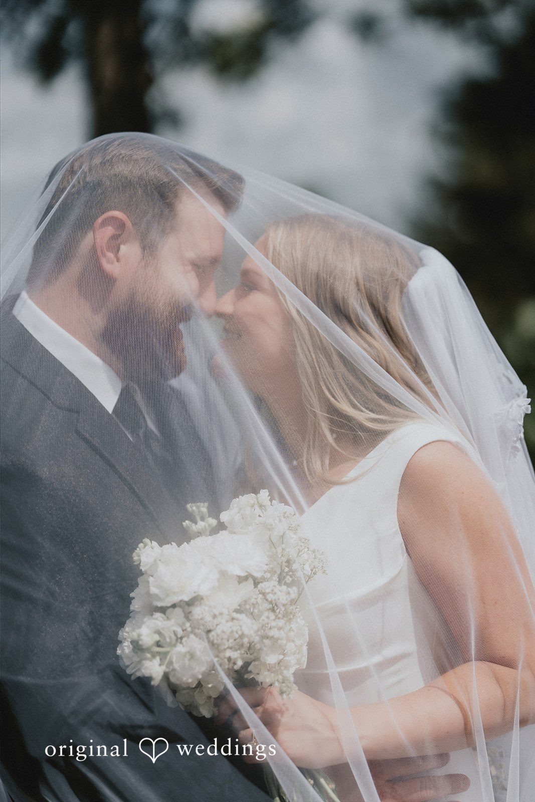 Close-up of the bride and groom captured through a sheer veil.