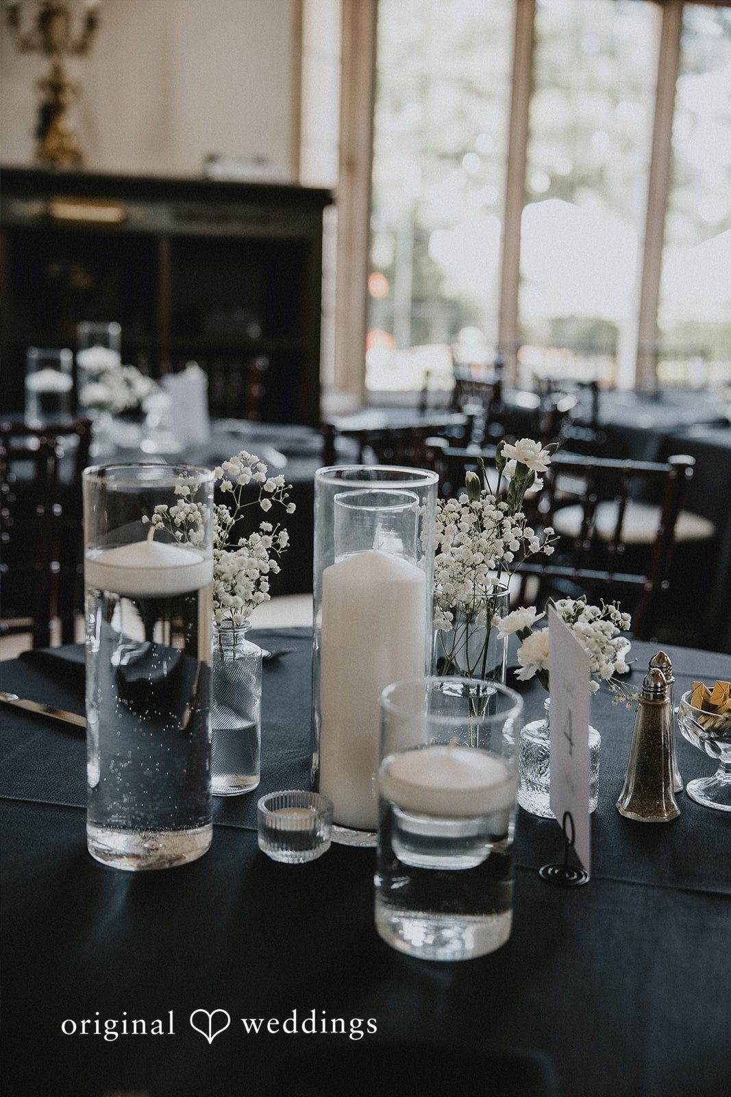 Table centerpiece featuring candles in clear glass vases.