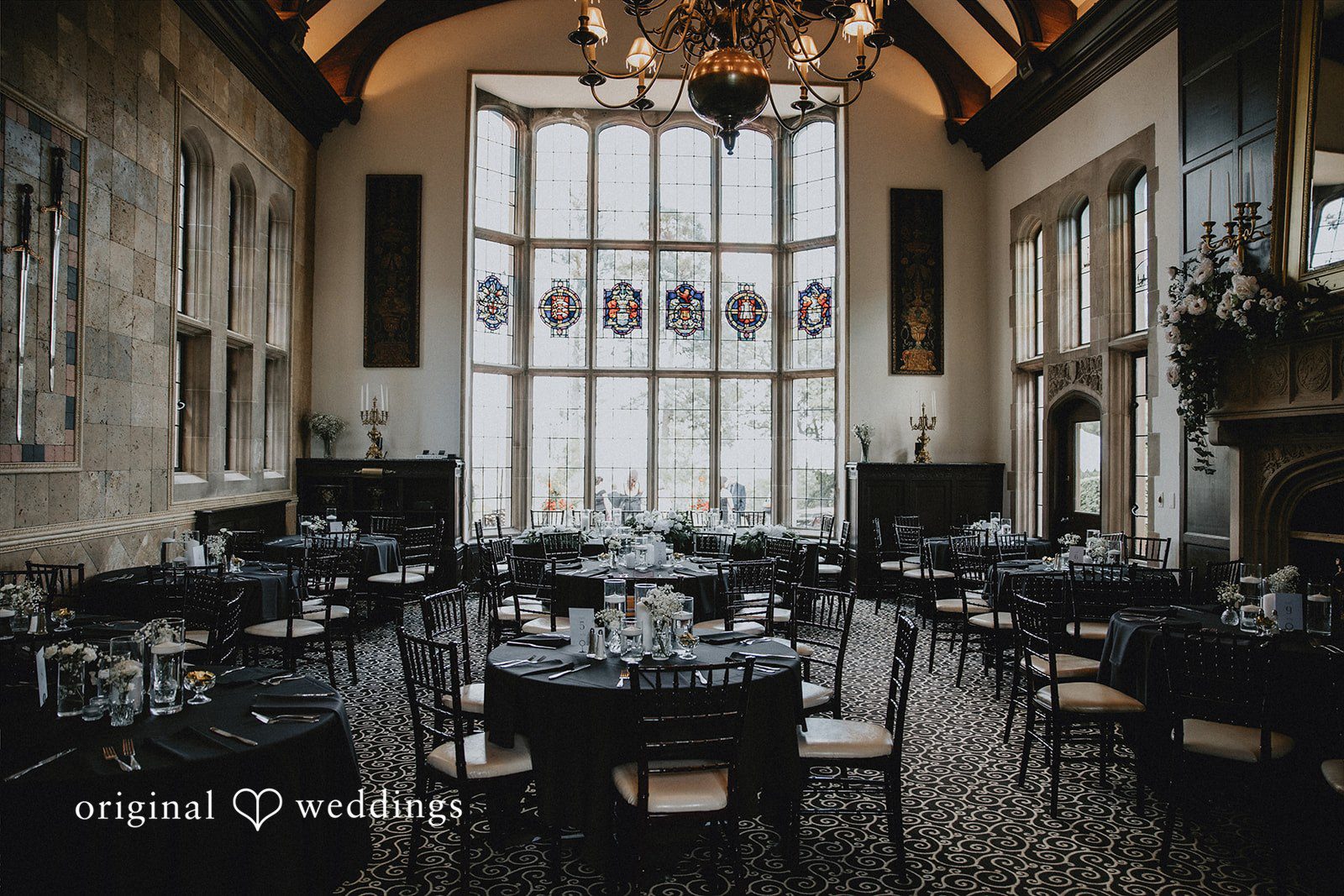 Elegant reception hall set up with dark tables and chairs.
