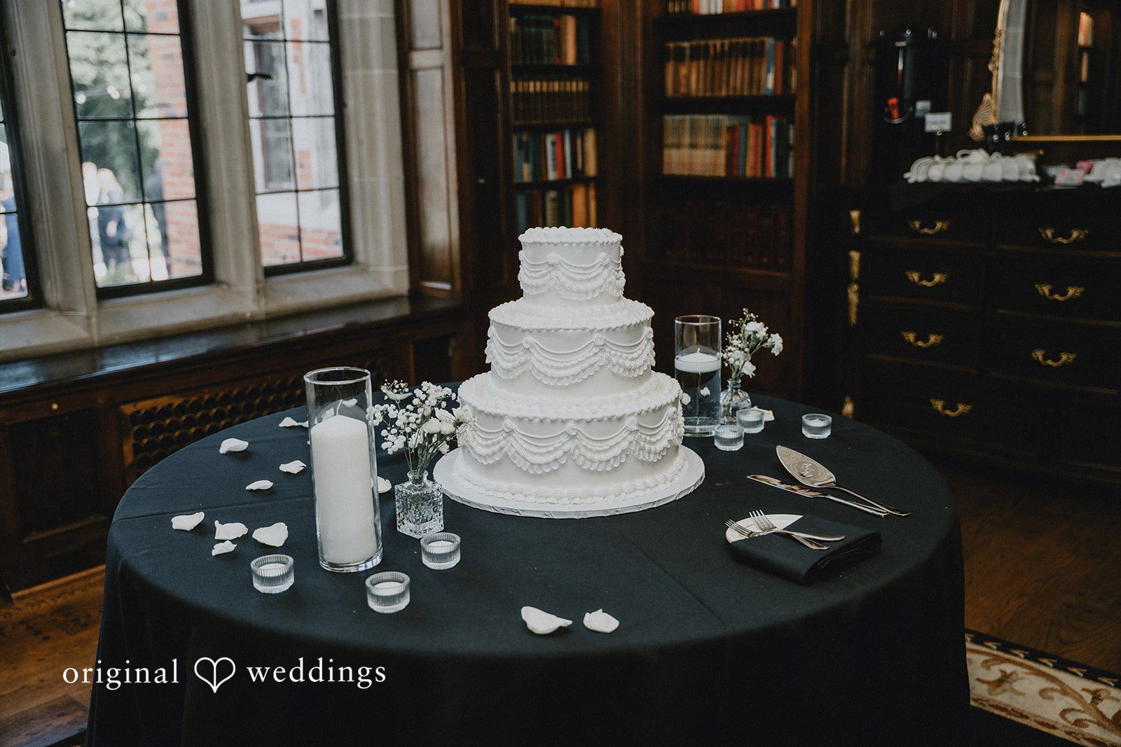 Multi-tiered white wedding cake displayed on a round table.
