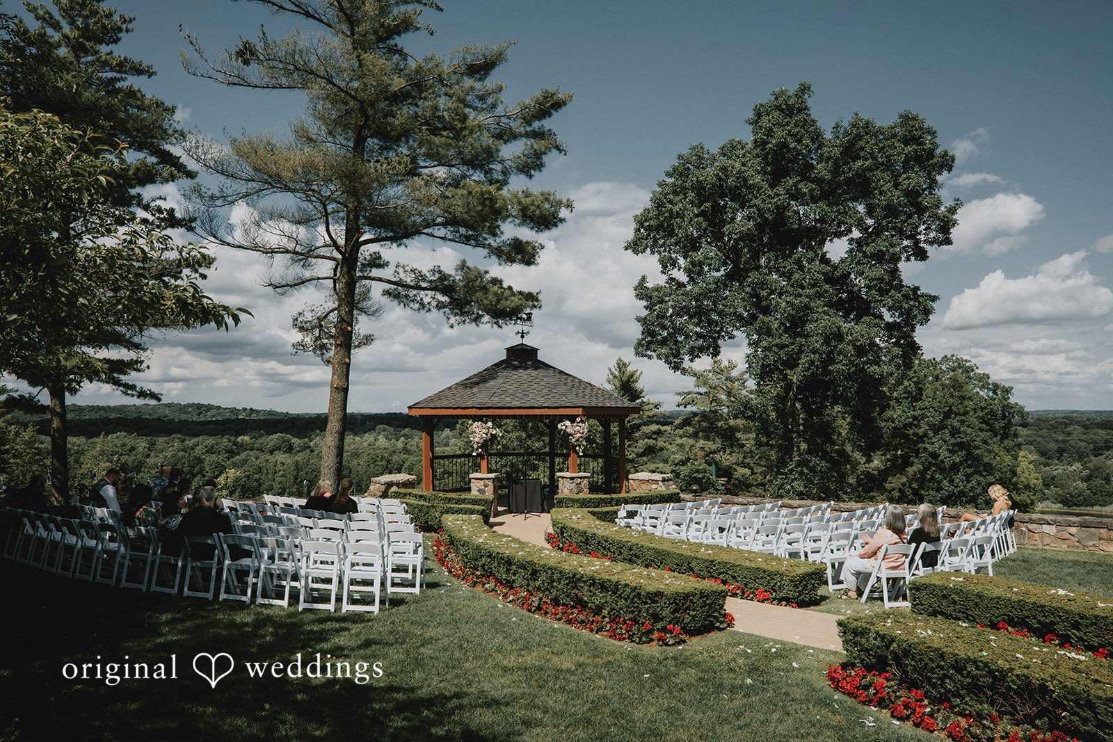 Garden wedding ceremony aisle with rows of white chairs at Pine Knob Mansion.