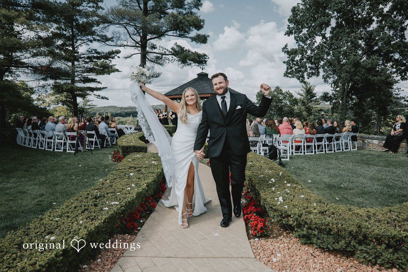 Bride and groom walking down an aisle holding hands.