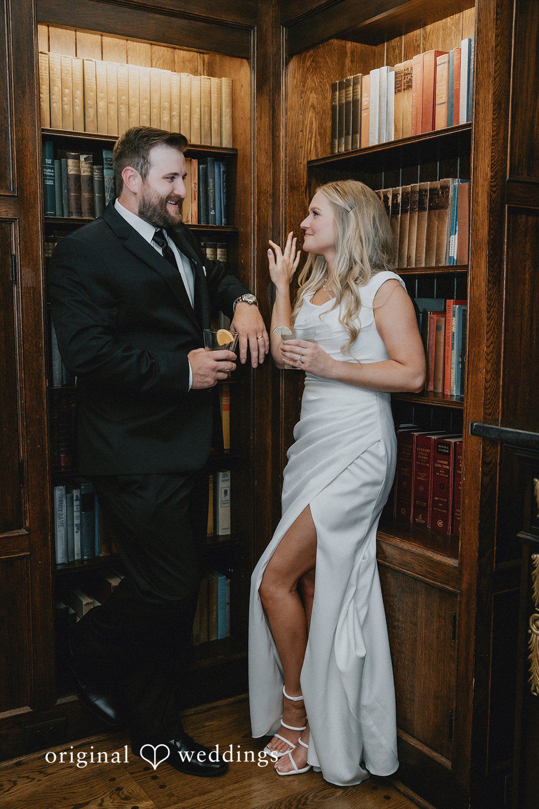 Bride and groom sharing a playful moment inside a library.