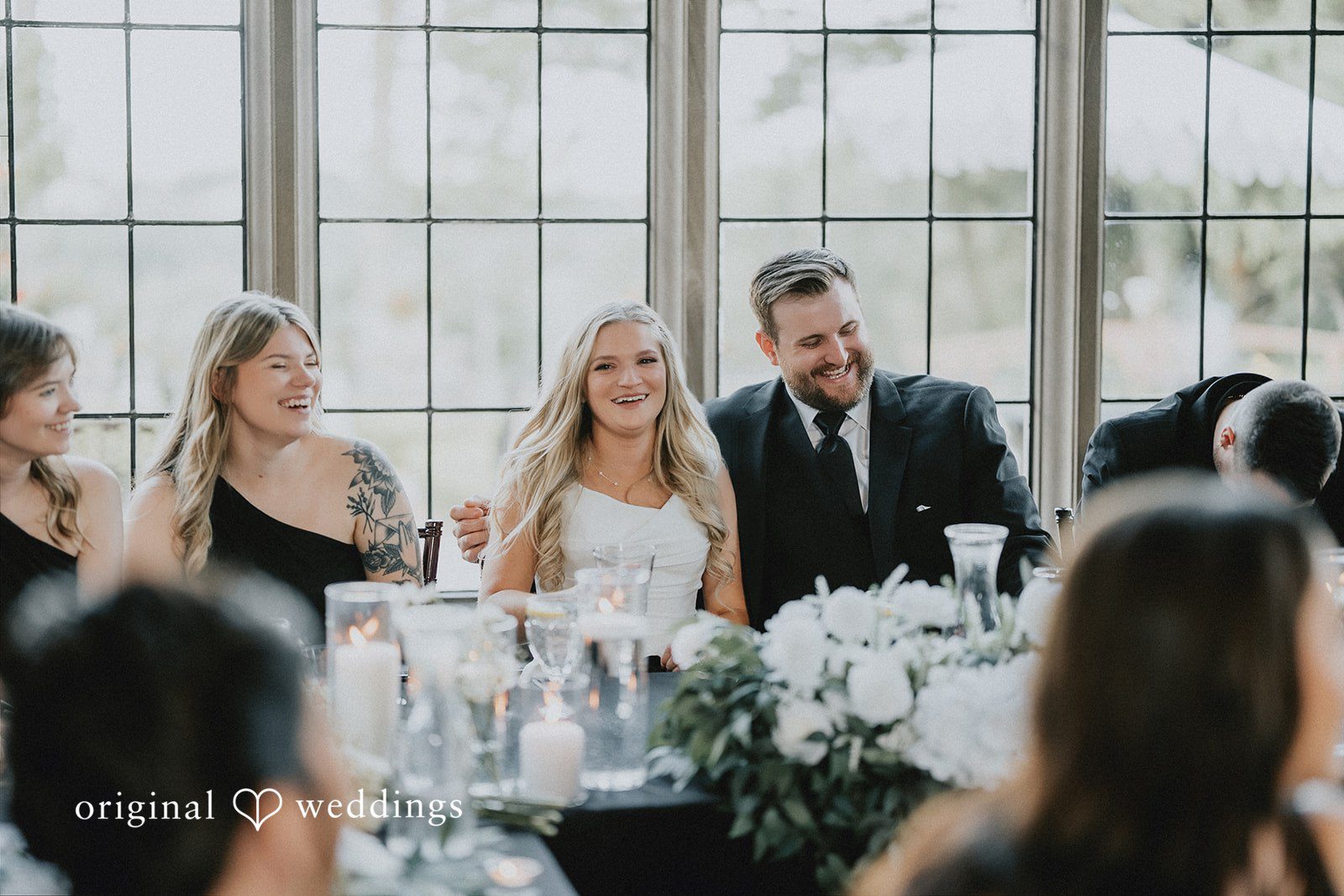 Bride and groom chatting with guests at a reception table.