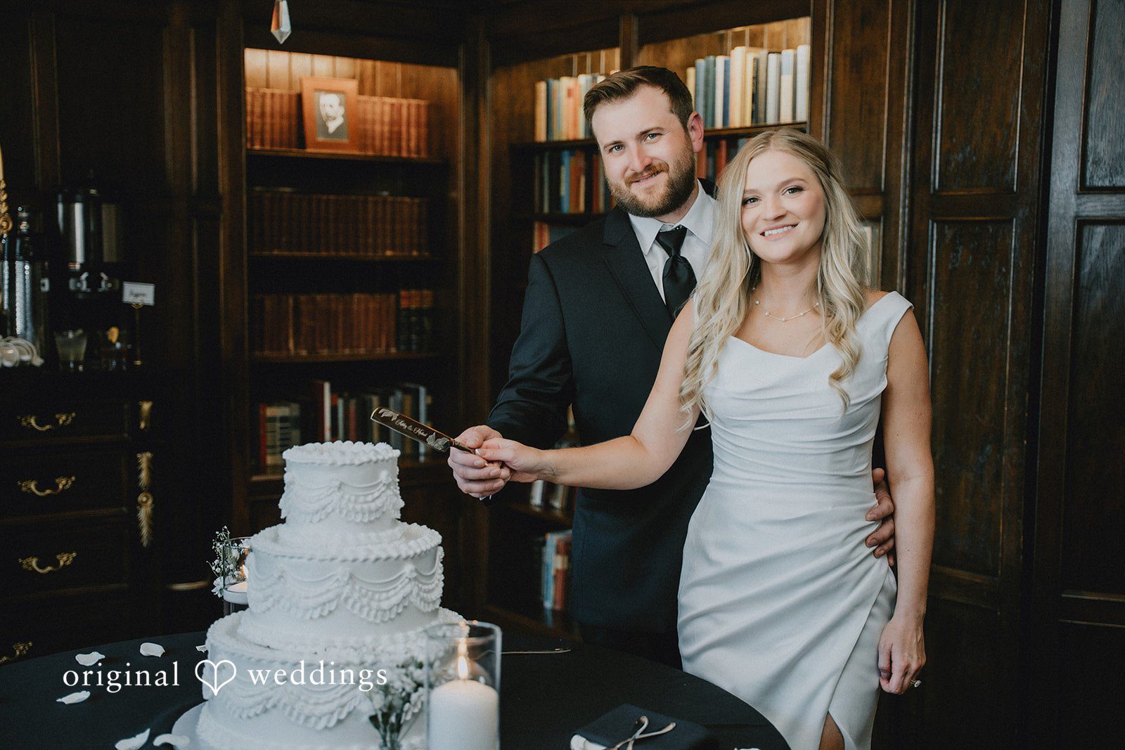 Bride and groom cutting their multi-tiered white wedding cake.