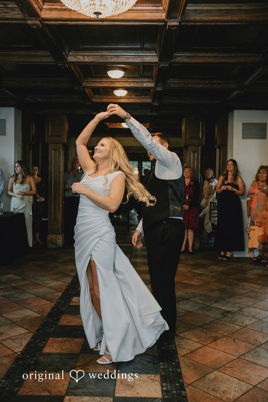 Bride spinning around while dancing on a tiled reception floor.