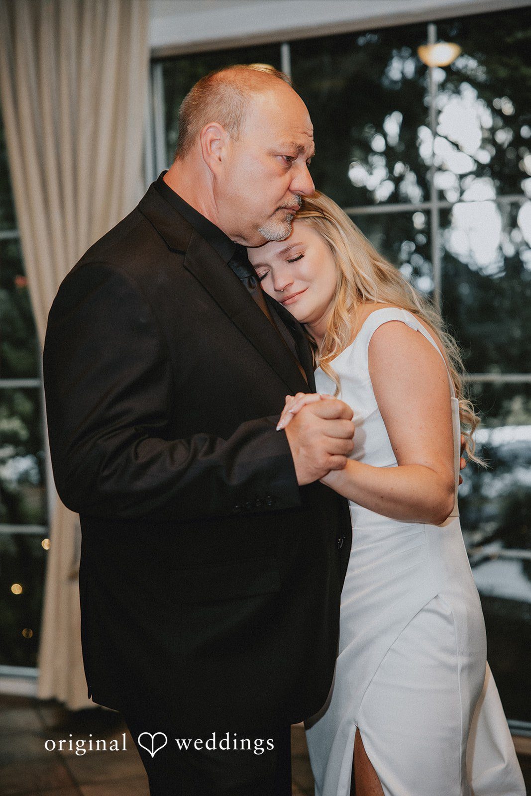 Bride resting her head on a man's shoulder during a dance.