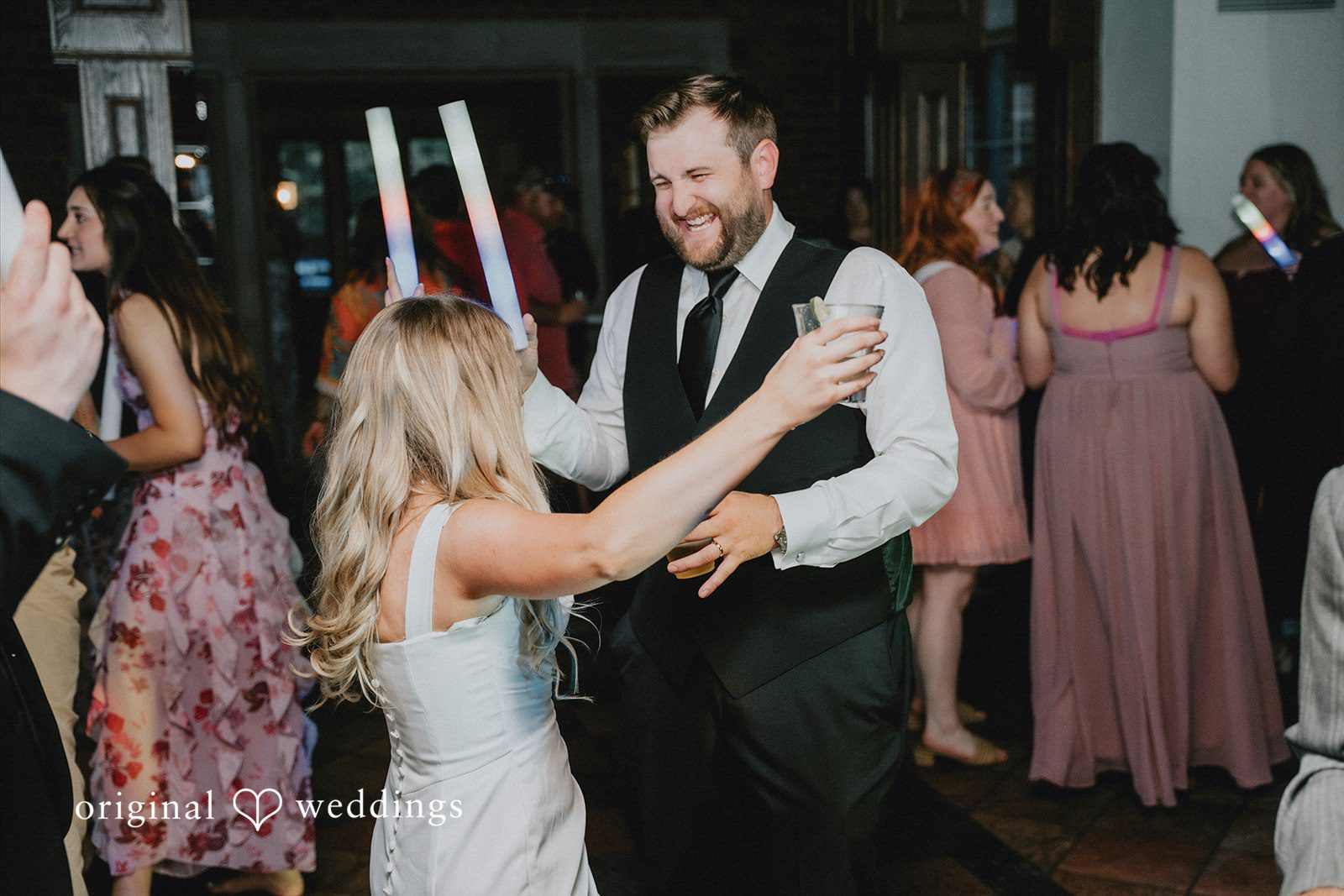 Bride laughing while dancing with a smiling man at the reception.